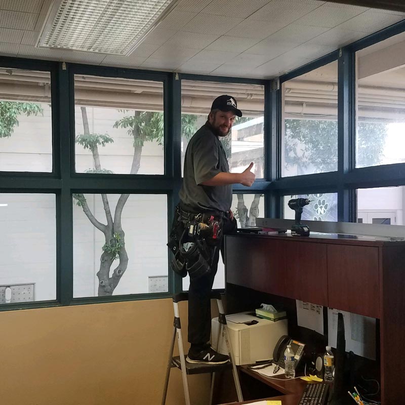 man installing window coverings